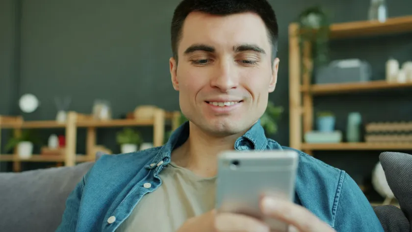 Hombre sonriendo con confianza mientras usa la app desde su teléfono